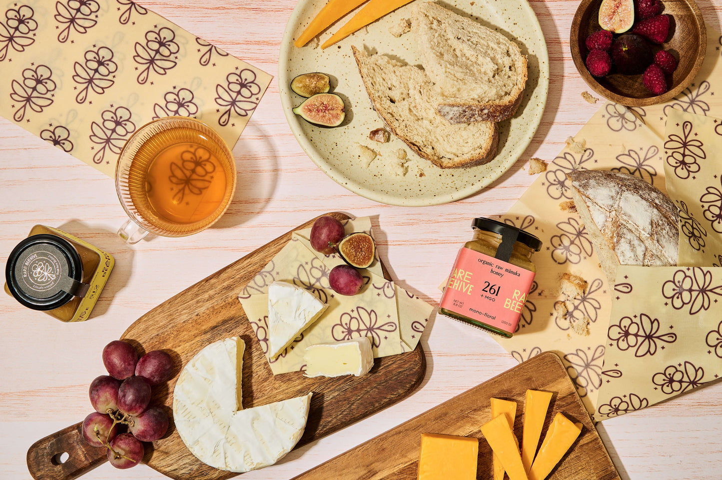 the beeswax wrap | RARE Essentials showcased with cheese, bread, fruit, and tea on a rustic table.